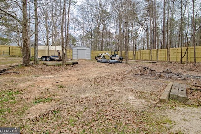 view of yard featuring a storage shed, an outdoor structure, and fence