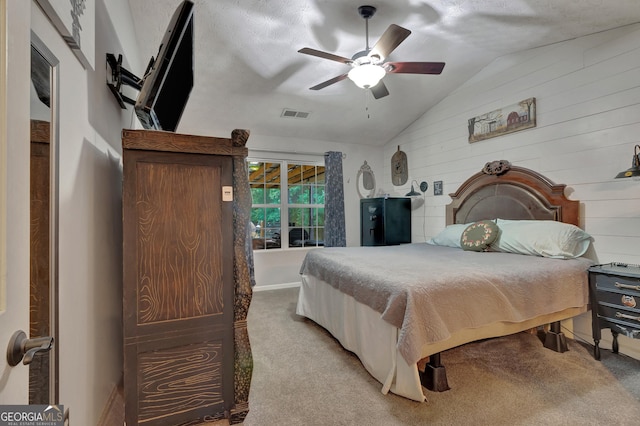 bedroom with lofted ceiling, wood walls, carpet flooring, visible vents, and a ceiling fan