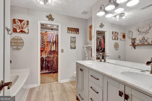 full bathroom featuring a textured ceiling, visible vents, and a sink