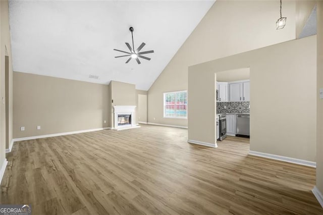 unfurnished living room with ceiling fan, baseboards, wood finished floors, and a glass covered fireplace