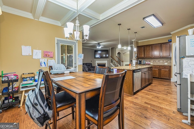 kitchen with a kitchen island with sink, stainless steel appliances, a fireplace, light wood-style floors, and tasteful backsplash