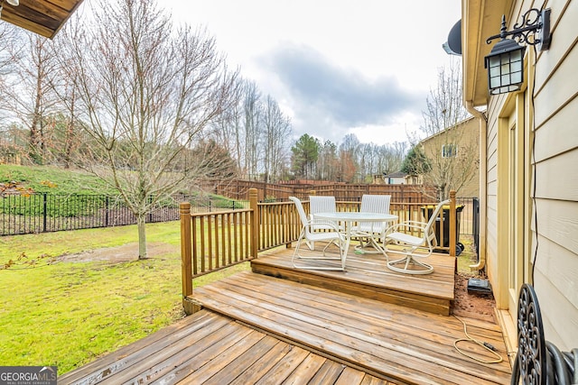 deck featuring outdoor dining space, a fenced backyard, and a lawn