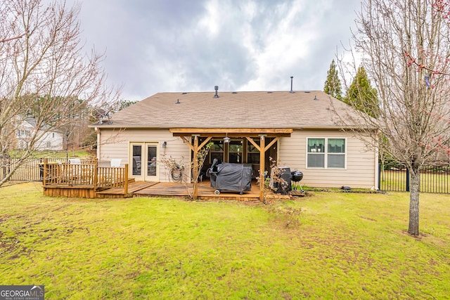 rear view of house with a deck, a yard, and fence