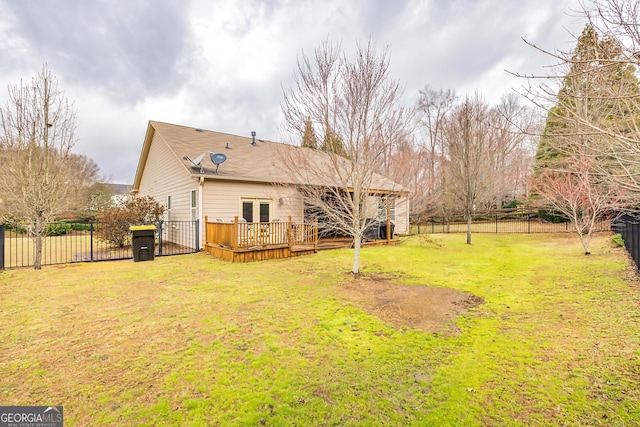 rear view of property with a fenced backyard, a shingled roof, a deck, and a lawn