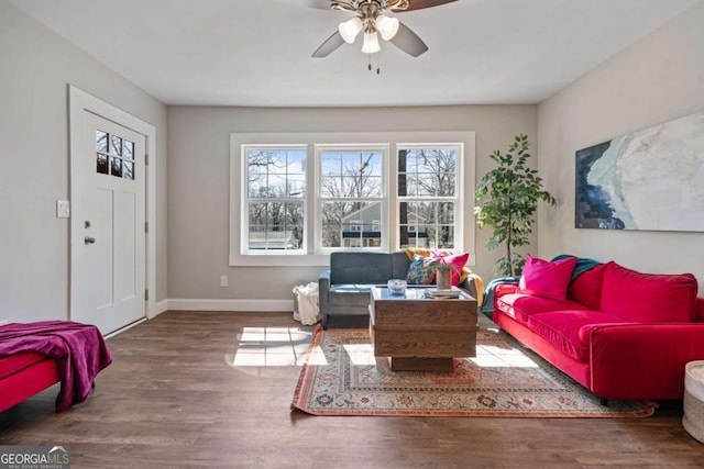 living room with ceiling fan, baseboards, and wood finished floors