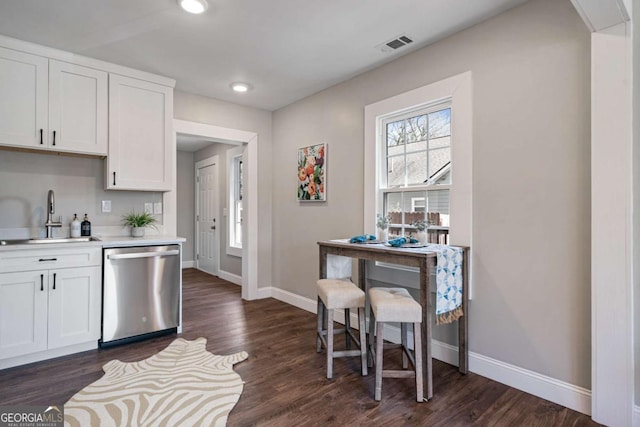 kitchen featuring visible vents, baseboards, dishwasher, light countertops, and a sink