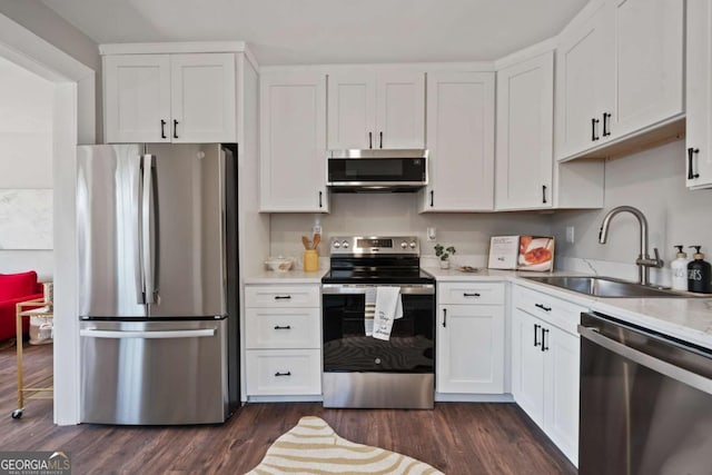 kitchen featuring dark wood-style flooring, a sink, light countertops, appliances with stainless steel finishes, and white cabinetry