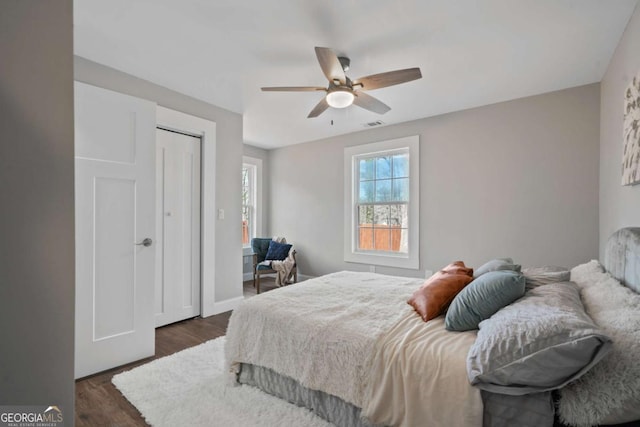 bedroom featuring a closet, baseboards, dark wood-type flooring, and a ceiling fan