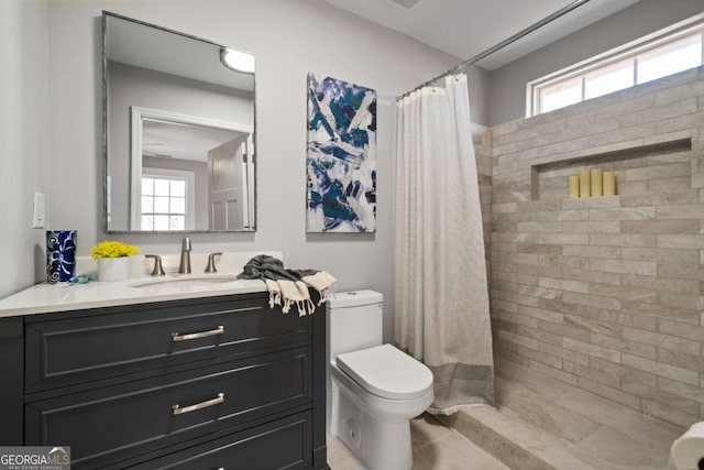 bathroom with vanity, toilet, and a tile shower