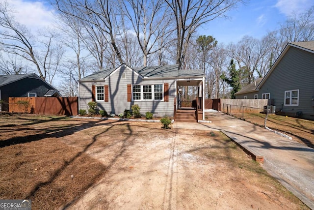 view of front of property featuring an attached carport, fence, concrete driveway, crawl space, and central air condition unit