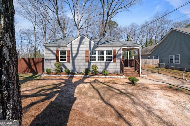 view of front of home with central air condition unit, a carport, driveway, and fence