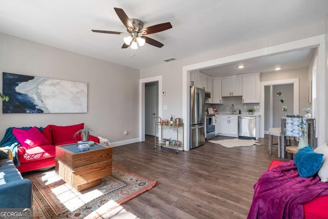 living room with ceiling fan, visible vents, baseboards, and dark wood-style floors