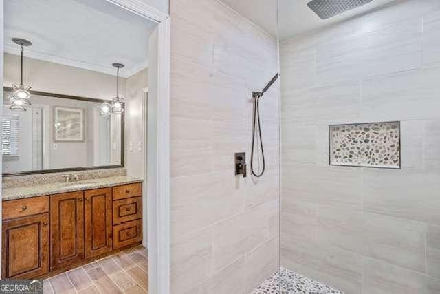 bathroom featuring ornamental molding, tiled shower, wood finished floors, and vanity