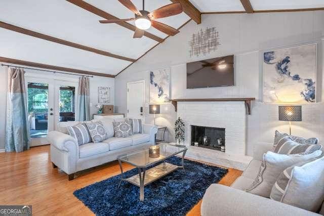 living area with french doors, beam ceiling, a fireplace, ceiling fan, and wood finished floors