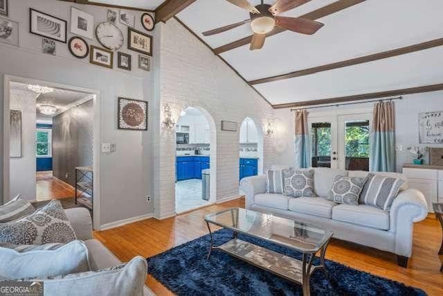 living room featuring arched walkways, french doors, ceiling fan, wood finished floors, and high vaulted ceiling