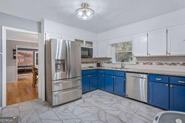 kitchen with white cabinets, appliances with stainless steel finishes, blue cabinets, light countertops, and a sink