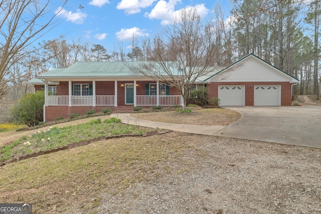 single story home featuring concrete driveway, metal roof, an attached garage, covered porch, and brick siding