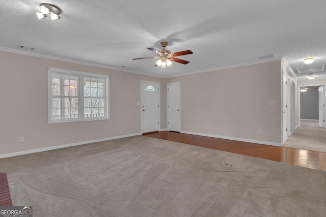 unfurnished living room featuring ceiling fan, carpet flooring, visible vents, baseboards, and ornamental molding