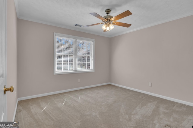 carpeted empty room with visible vents, ornamental molding, ceiling fan, a textured ceiling, and baseboards