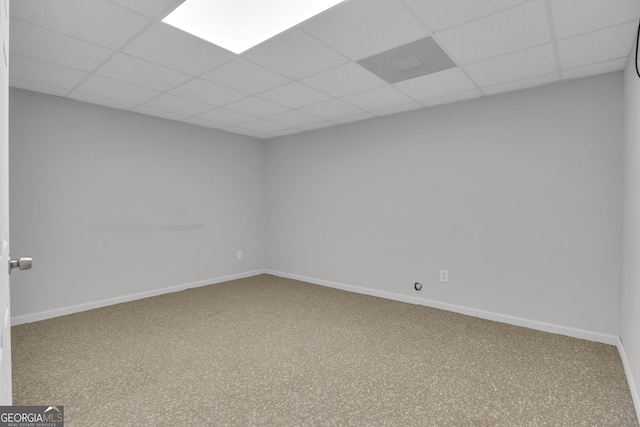 unfurnished room featuring a paneled ceiling, carpet, and baseboards