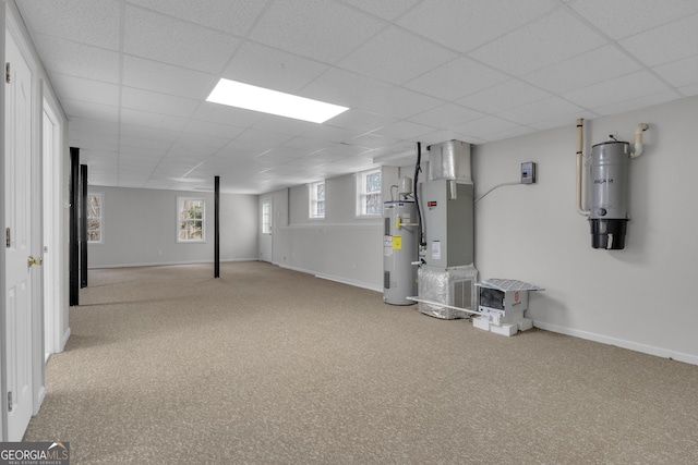 below grade area featuring water heater, carpet, a paneled ceiling, and baseboards