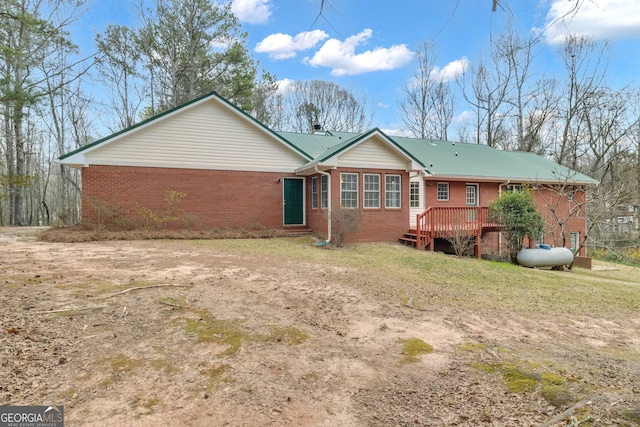 rear view of property featuring metal roof and brick siding