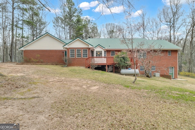 rear view of house featuring metal roof, brick siding, a lawn, and a wooden deck