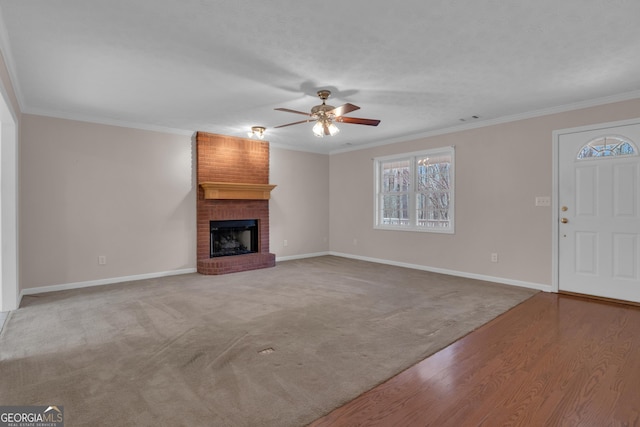 unfurnished living room with crown molding, a fireplace, baseboards, and ceiling fan