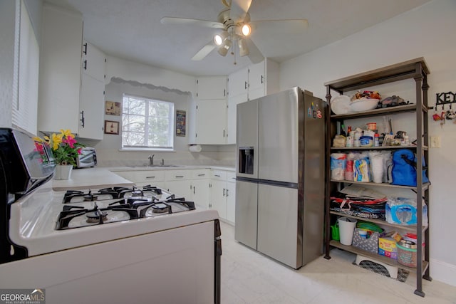 kitchen featuring white cabinetry, light countertops, stainless steel fridge with ice dispenser, and white gas range oven