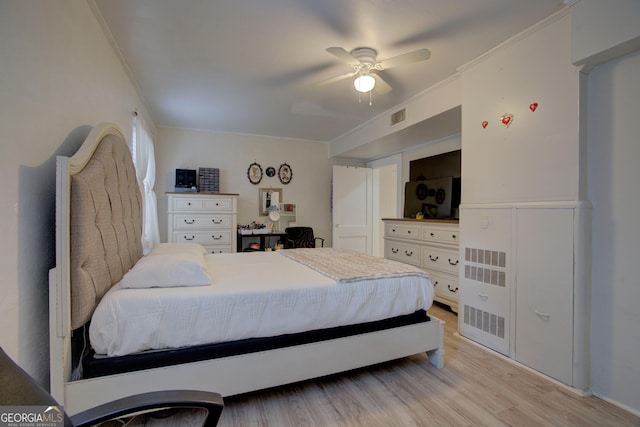 bedroom featuring visible vents, crown molding, light wood finished floors, and ceiling fan