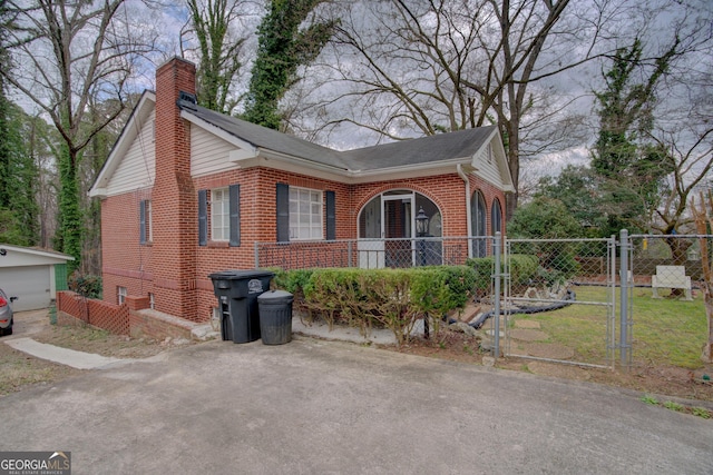 view of side of property featuring brick siding, a chimney, fence, and a gate