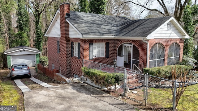 view of front of property with a porch, brick siding, a detached garage, fence, and a chimney