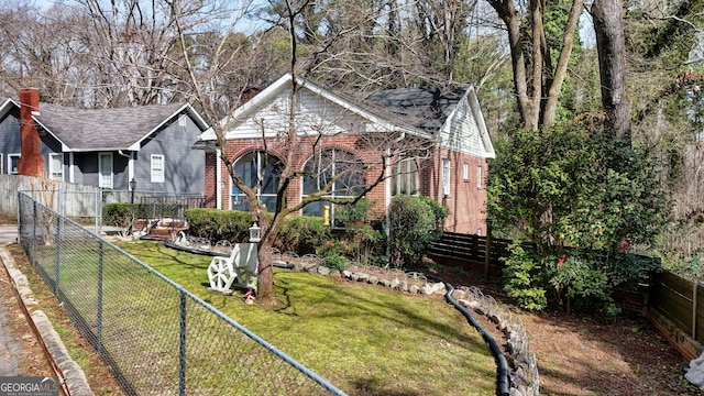 view of front of property featuring brick siding, a front lawn, and a fenced backyard