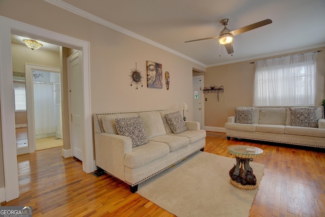 living area featuring baseboards, crown molding, a ceiling fan, and wood finished floors