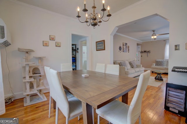 dining room with arched walkways, ornamental molding, ceiling fan with notable chandelier, and light wood-type flooring