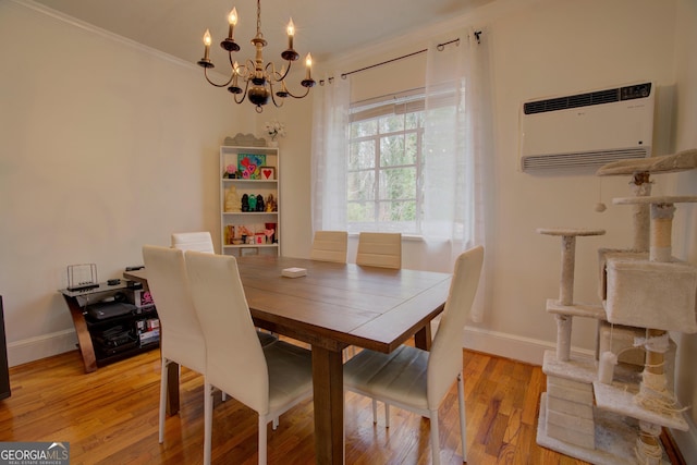 dining room featuring a wall unit AC, ornamental molding, light wood-style floors, a chandelier, and baseboards