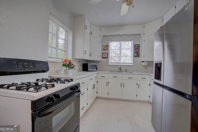 kitchen with range with gas stovetop, a healthy amount of sunlight, stainless steel fridge, and a sink