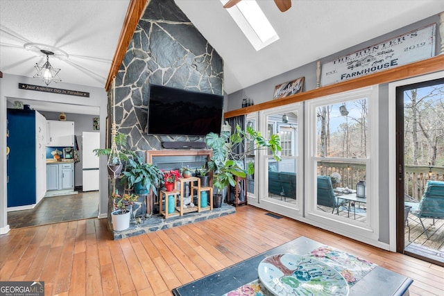 living room with vaulted ceiling with skylight, wood-type flooring, and visible vents