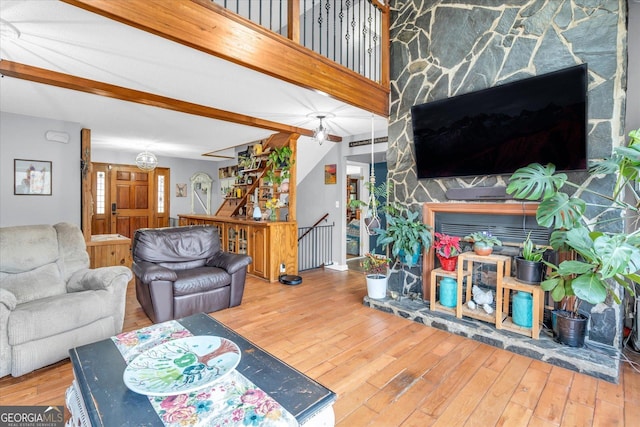 living area featuring stairway, wood finished floors, and beam ceiling