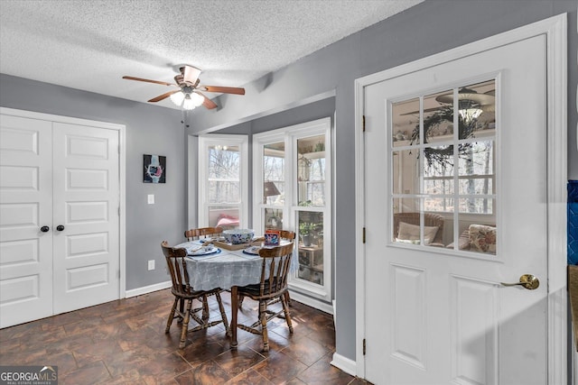 dining space featuring ceiling fan, baseboards, and a textured ceiling