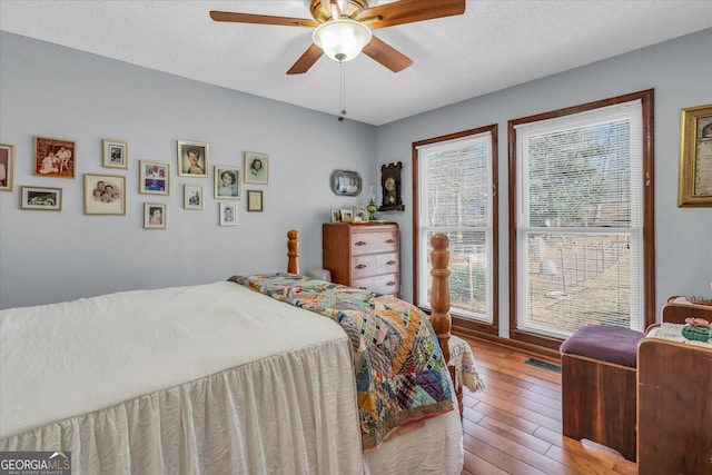 bedroom featuring ceiling fan, a textured ceiling, and wood finished floors