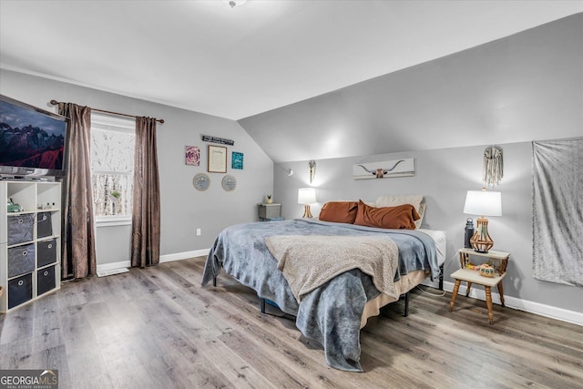 bedroom with lofted ceiling, wood finished floors, and baseboards