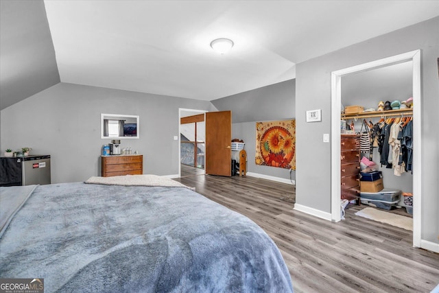 bedroom featuring lofted ceiling, baseboards, and wood finished floors