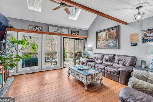 living area with visible vents, lofted ceiling with skylight, a textured ceiling, wood finished floors, and ceiling fan with notable chandelier