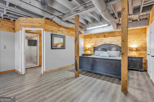 bedroom featuring wood walls, baseboards, and wood finished floors