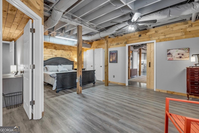 bedroom featuring wooden walls, baseboards, and wood finished floors