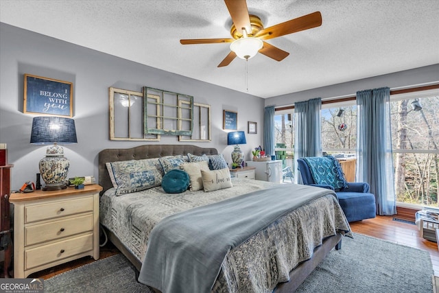 bedroom with a ceiling fan, a textured ceiling, and wood finished floors