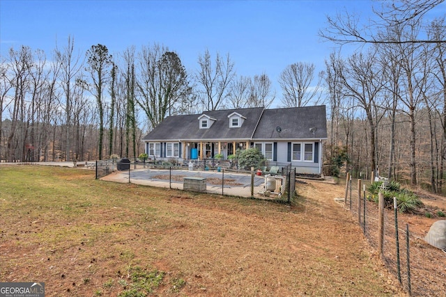 view of front of home with a patio area, fence, a front lawn, and a wooded view