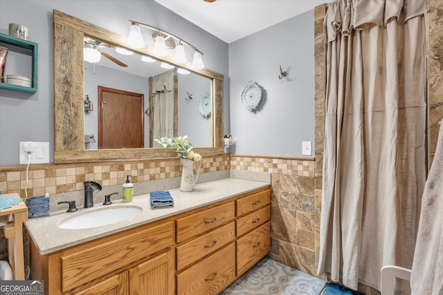 full bathroom featuring wainscoting, tile walls, vanity, and a ceiling fan