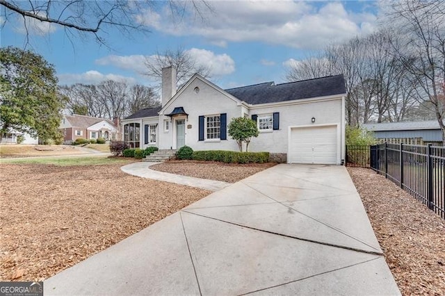 view of front facade with driveway, a chimney, an attached garage, and fence